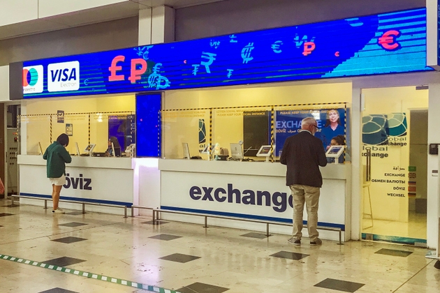 Two people in front of foreign currency exchange kiosk