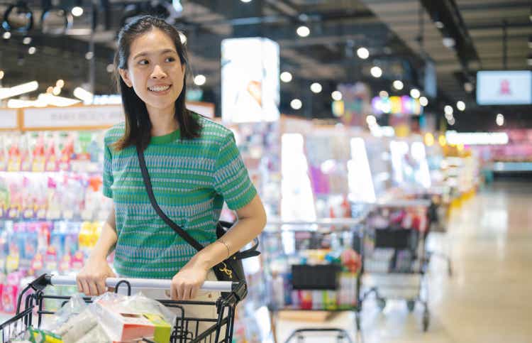 Weekend shopping time at Discount store Young 30S cheerful Asian woman with psuhing cart shopping with cart trolley grocery choosing buy products in supermarket Thailand