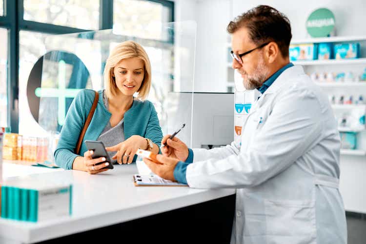 Mid adult woman buying prescription medicine in drugstore.