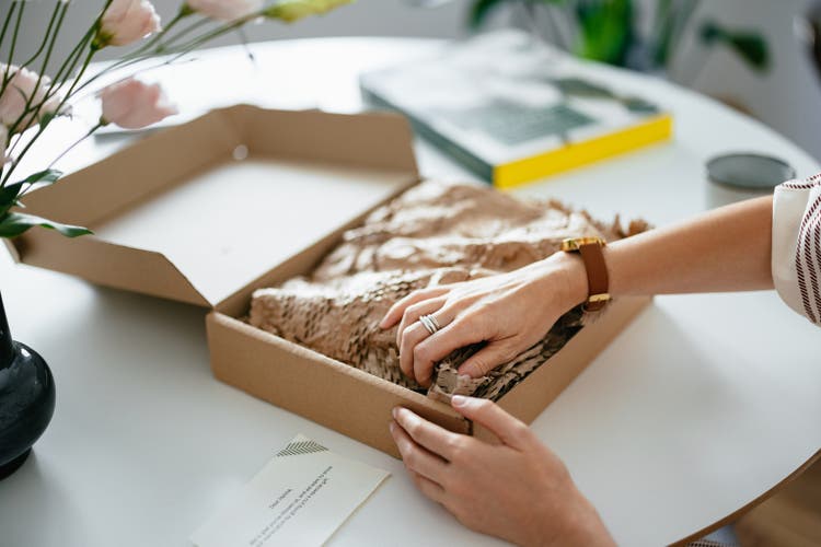 Mujer anónima desenvolviendo la caja de regalo