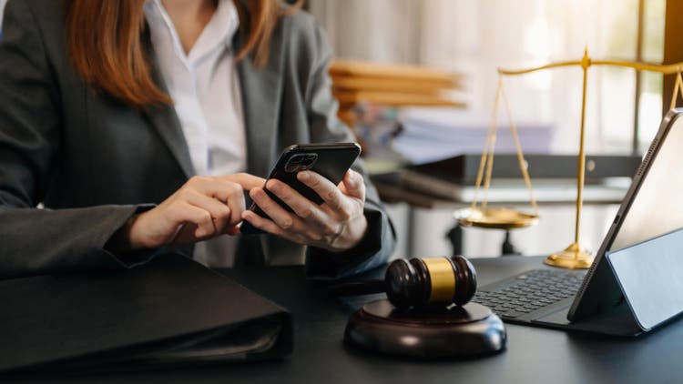 justice and law concept. Male judge in a courtroom the gavel, working with smart phone and laptop and digital tablet computer on wood table