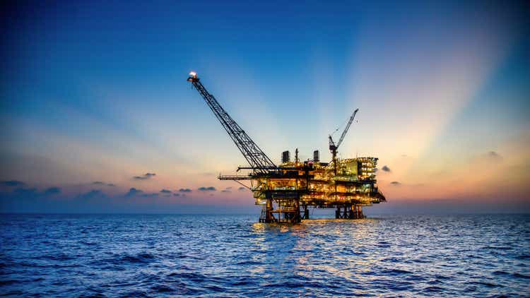 Offshore oil and rig platform in sunset or sunrise time. Construction of production process in the sea. Power energy of the world.