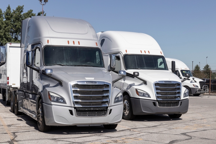 Freightliner Big Rig Semi Tractor Trailer Trucks on display at a dealership. Freightliner is owned by Daimler.