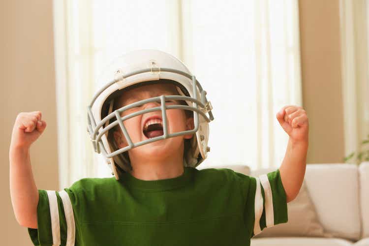 Cheering Caucasian boy in football uniform