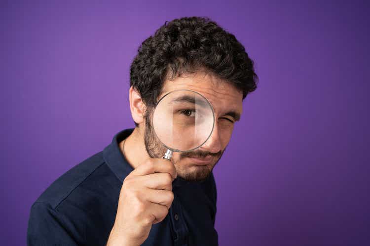thesis center Man looking through magnifying glass