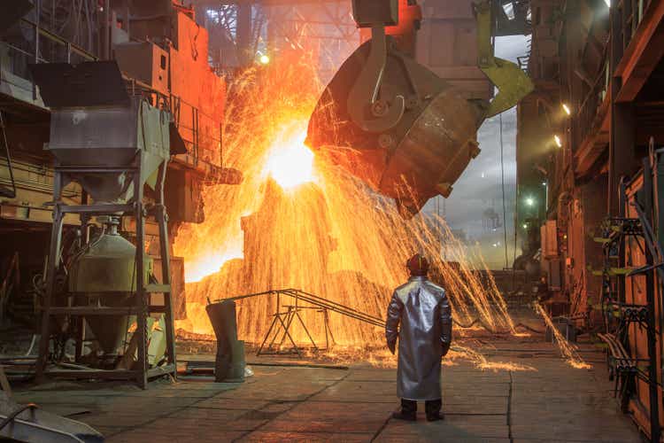 Hot steel pouring from big casting ladle into a mold in an iron foundry.