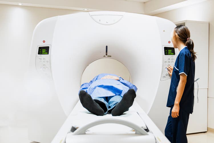Patient undergoing MRI scan in a diagnostic imaging facility with technician operating the machine