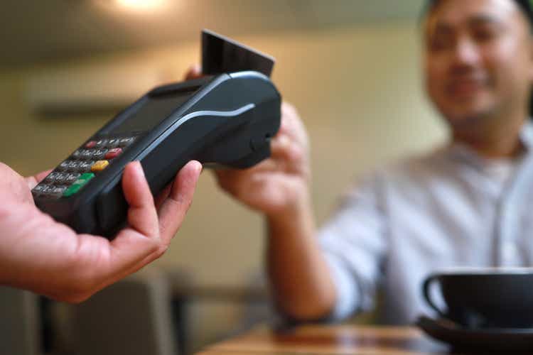 Attractive Asian man using contactless technology in cafe