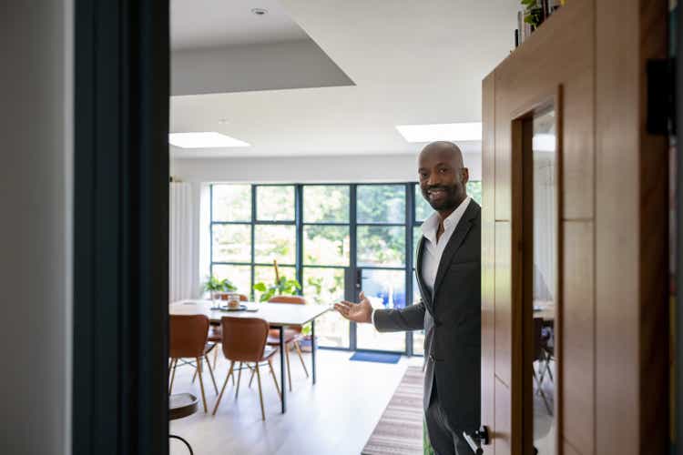 Welcoming real estate agent opening the door of a house for sale