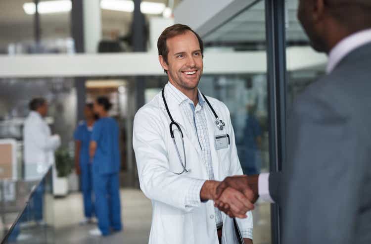 Doctor shaking hands with corporate business man for deal, meeting and healthcare contract. Handshake, consulting and b2b partnership in medical office for opportunity agreement and insurance support