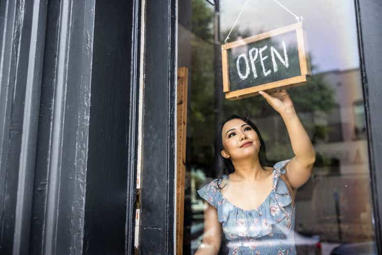 Female small business owner turning open sign in her store