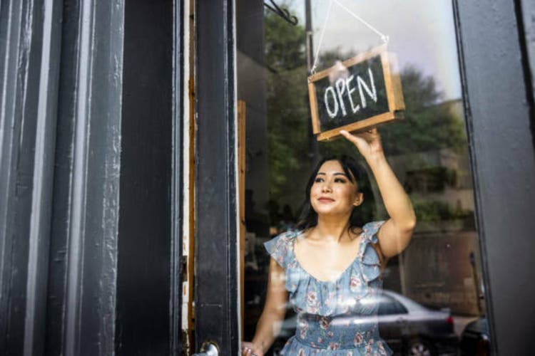 Female small business owner turning open sign in her store