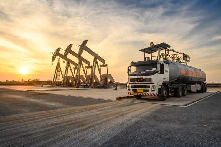 Oil field site, in the evening, oil pumps and oil truck