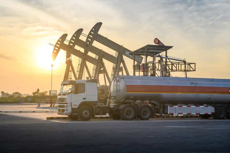 Oil field site, in the evening, oil pumps and oil truck
