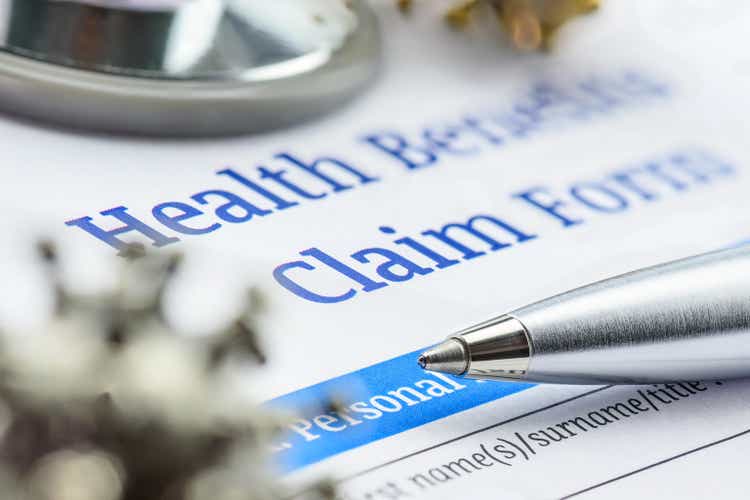 Covid-19 insurance claim, disease caused by a virus, healthcare concept : Coronavirus model on a health benefits form with a pen and a stethoscope, a patient"s insurance policy will cover all costs.