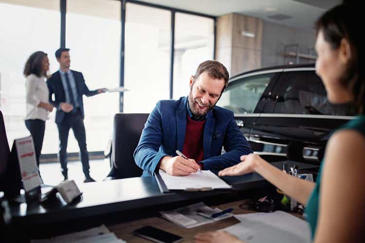 Man is buying/leasing new car and signing a contract