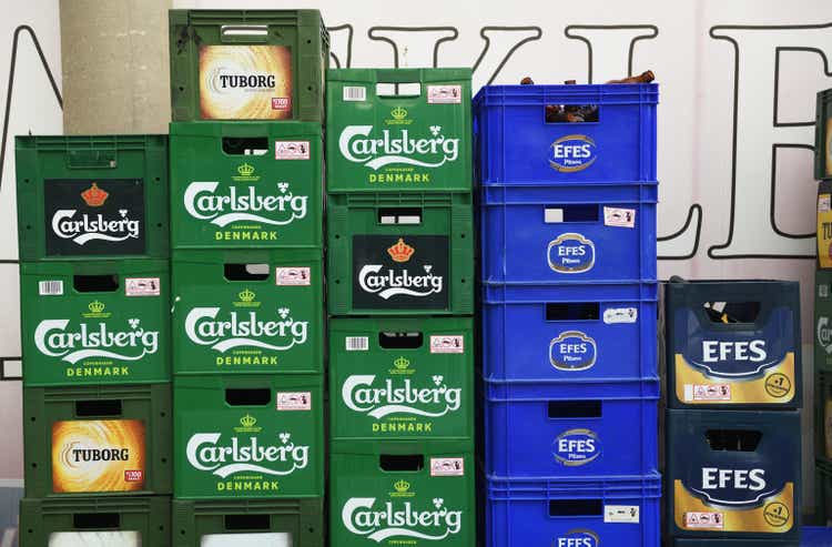 Crates of Carlsberg, Efes, Tuborg beer stand on the street near the store.