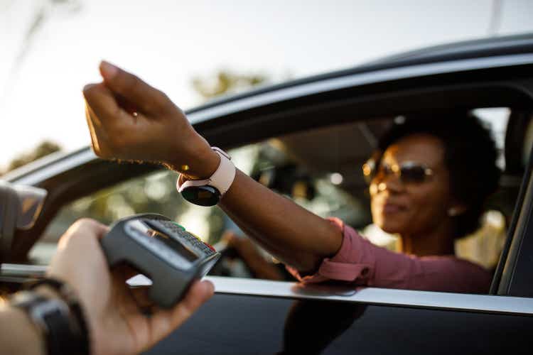 Selective focus shot of woman using smart watch to pay for drive through order