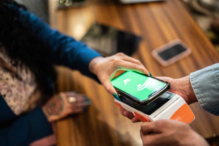 Close-up of woman paying with a mobile phone in a restaurant