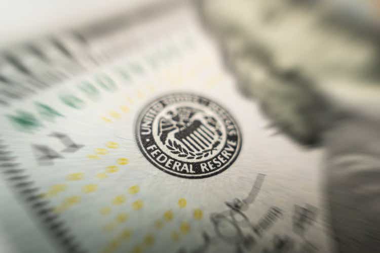 Enfoque selectivo en el emblema de la Reserva Federal de EE. UU. en billetes de cien dólares, ya que la FED considera el aumento de la tasa de interés, la economía y la organización nacional de control de la inflación.