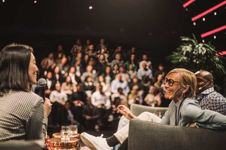 Interviewer interacting with smiling entrepreneurs during panel discussion at conference event
