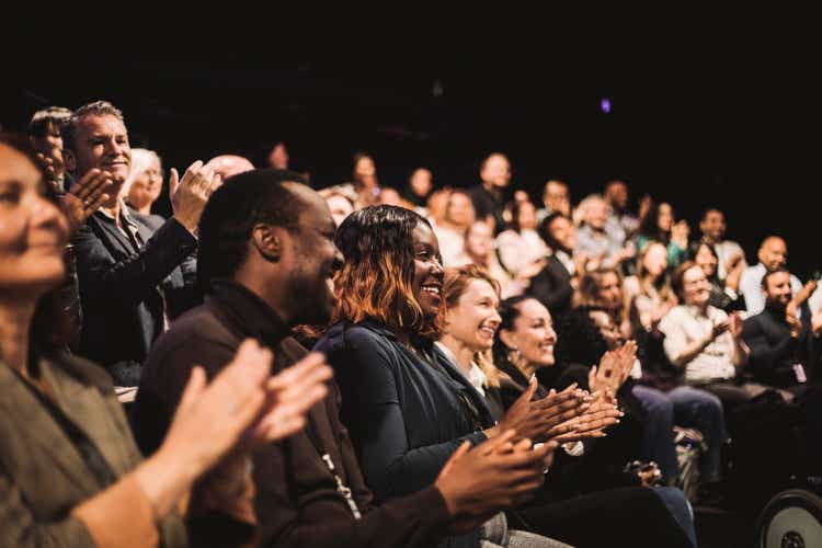 Smiling business colleagues applauding during conference event at convention center