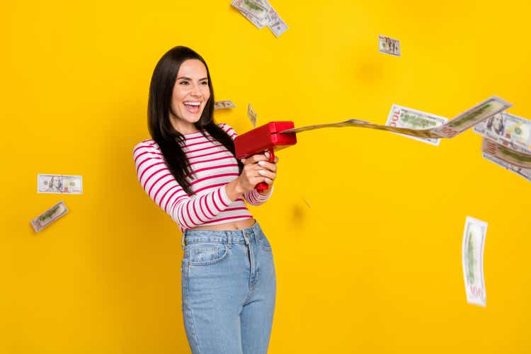 Photo of young attractive gorgeous crazy excited woman using gun pistol money throwing isolated on yellow color background