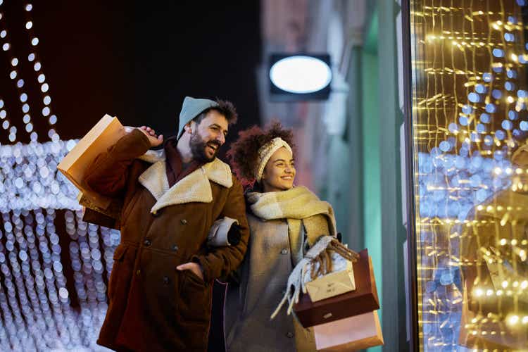 Happy couple having Christmas window shopping during the night on the street.