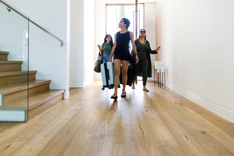 Full length of smiling woman with female friends entering villa