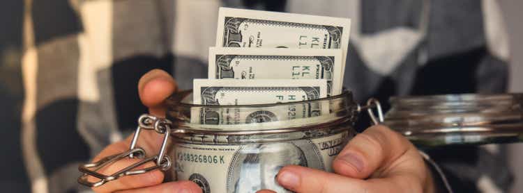 Dollar banknote saving money in glass jar. Banner Unrecognizable woman moderate consumption and economy Collecting money. Tips. Business, finance, saving, banking and people concept. Extra money, passive income