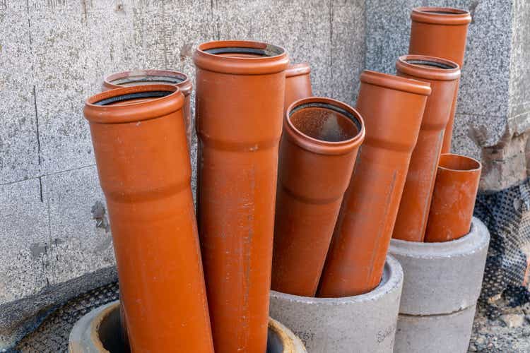 Stack of brown pvc pipes. Close up of orange plastic pipes on construction. Industrial background