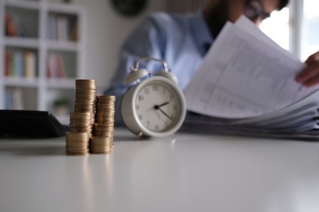 Businessman writing notes in documents model on stack of coins, in business, saving money