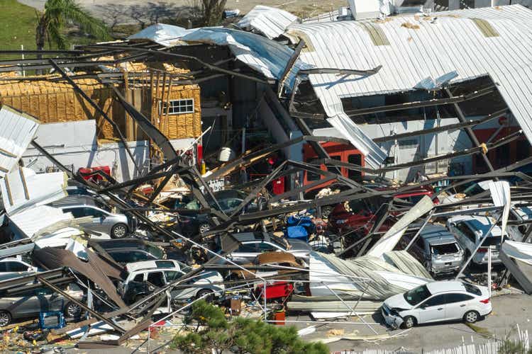 Hurricane Ian destroyed an industrial building with damaged cars in ruins in Florida.  Natural disaster and its consequences