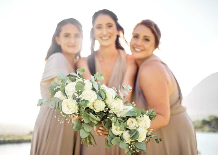 Wedding, flowers and happy bridesmaids with bouquet at party event for celebration, marriage and support. Creative, friends and roses with women holding floral arrangement for wedding reception