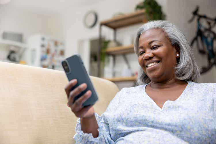 Woman at home looking happy watching videos on her cell phone