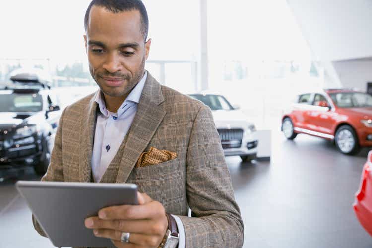Man using digital tablet in car dealership showroom