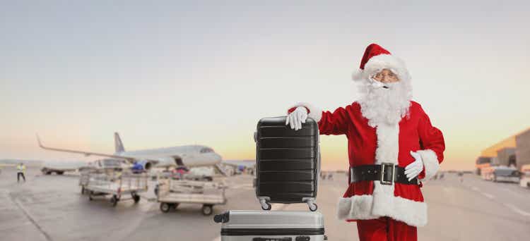 Santa claus standing on an airport apron and leaning on suitcases