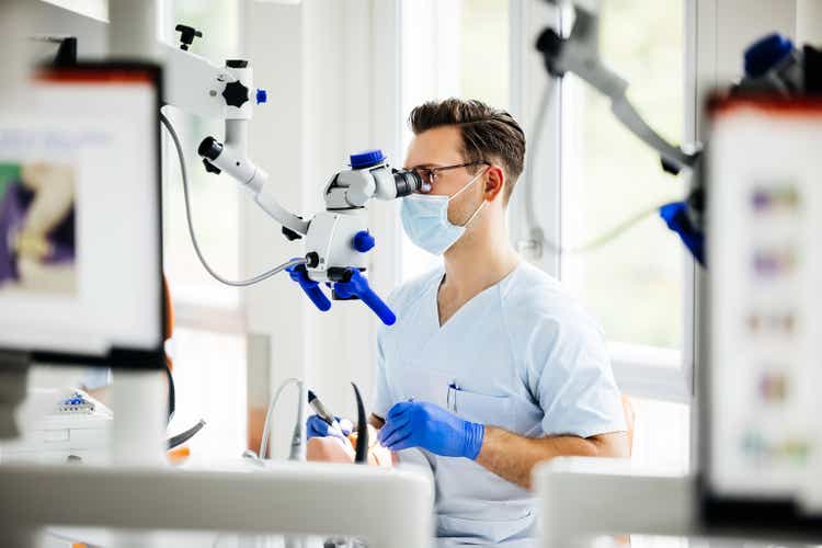 Student Dentist Looking Through Scope While Practicing Procedure