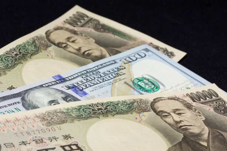 A single US $100 bill sandwiched between two 10,000 JPY bills