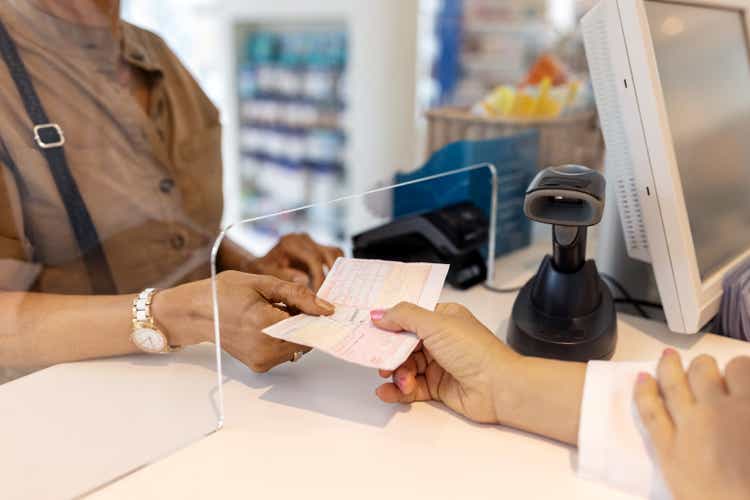 Close-up of a female hand writing a prescription to a pharmacist in a store