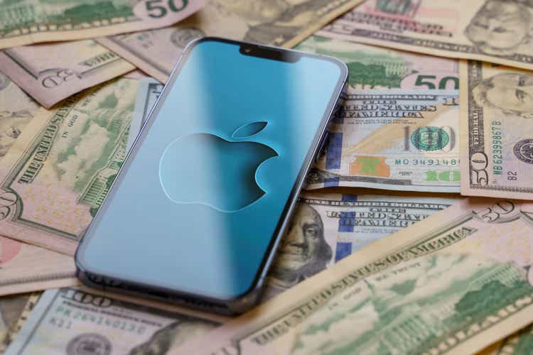 Lo smartphone Apple iPhone 13 Pro con logo Apple sullo schermo si erge sopra le banconote in dollari USA