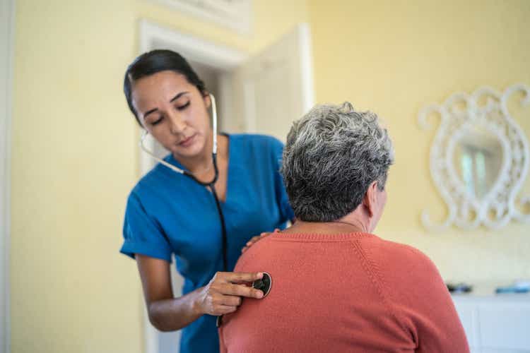 Mid adult nurse examining senior woman