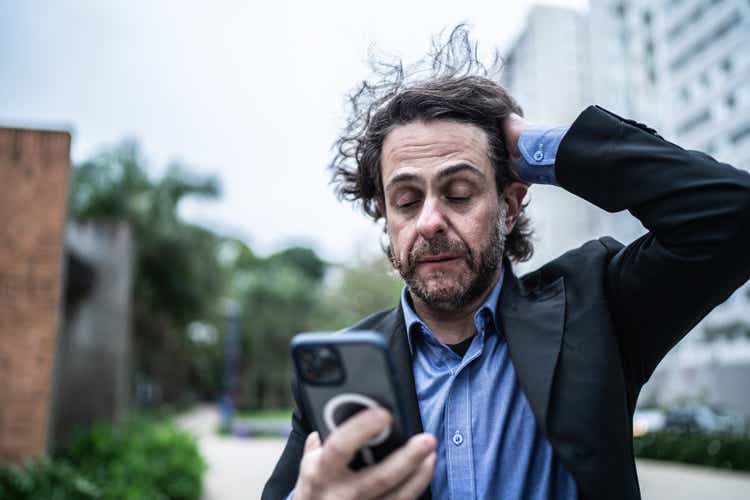 Worried mature businessman using the mobile phone in the street