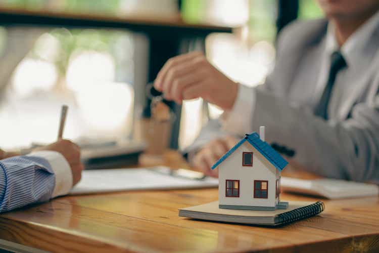 Sales representatives hand out the house keys to customers after signing a contract to buy a house or rent a new home on the table. concept of buying a house