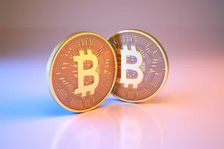 Bitcoin digital currency sitting on metallic blue and pink background