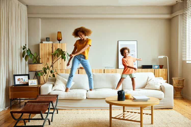Happy mother and son dancing on sofa at home