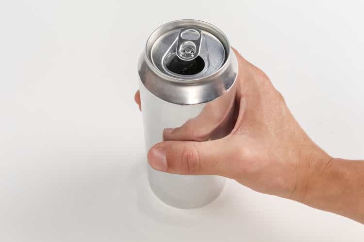 Person holding an open aluminum can on white background.