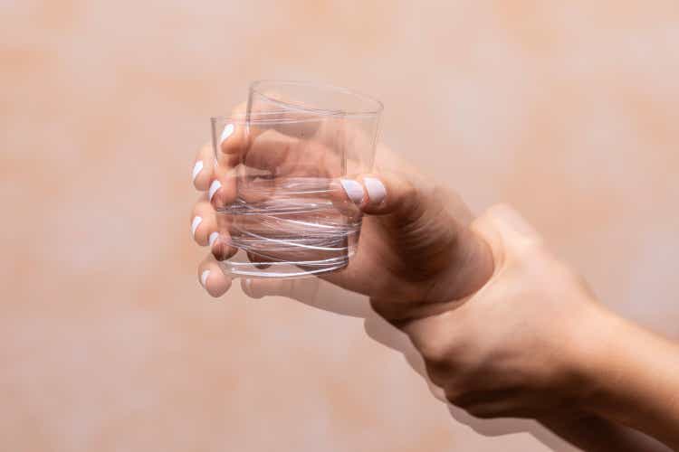 hand holding drinking glass suffering from Parkinson