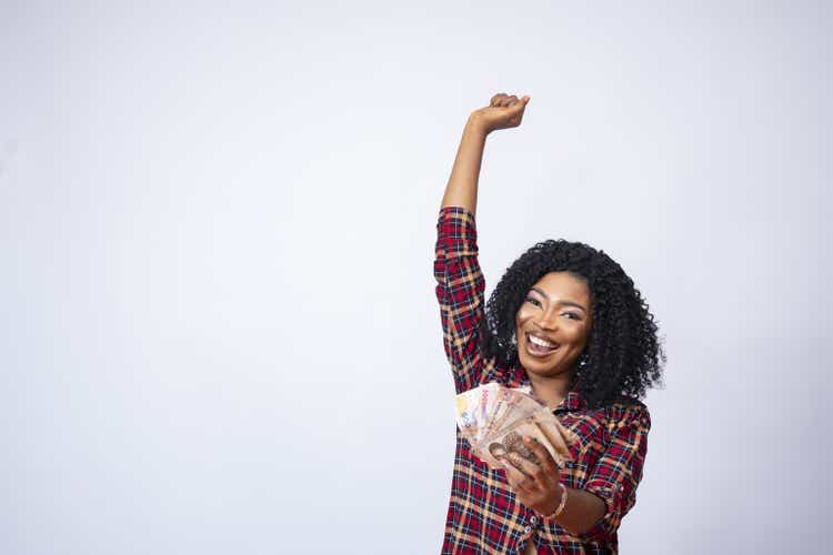 Pretty young black female holding a wad of cash expressing her excitement - business concept