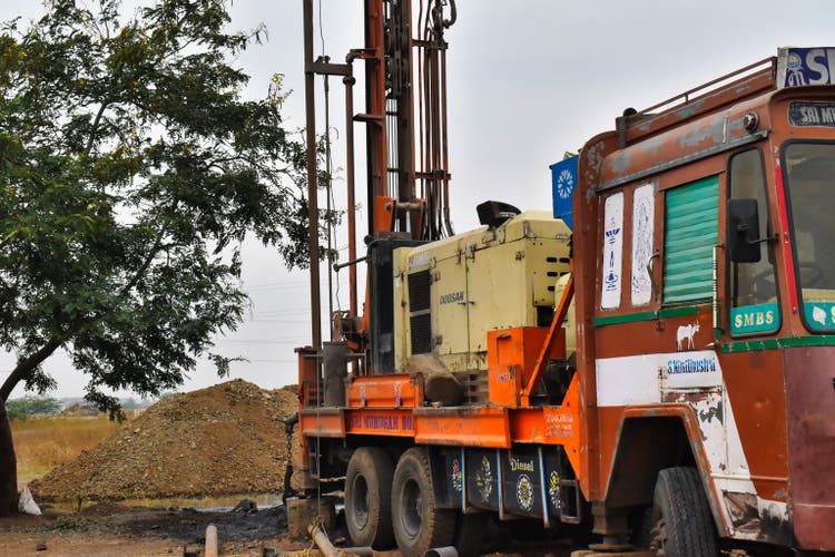 A labourer is tying the borewell drilling pipe with a rope and getting it stuck in the borewell drilling ring machine- Waterwell Drilling Machine